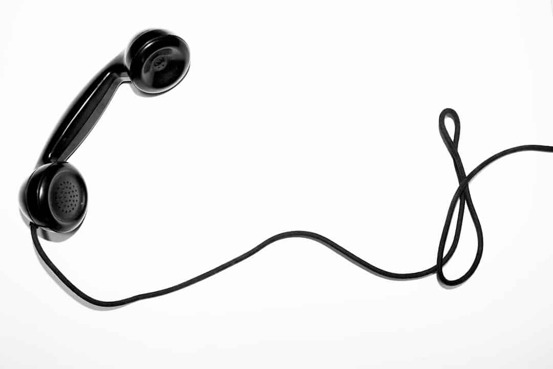 Osoba trzymająca telefon, z wyraźnie zniecierpliwioną lub zrezygnowaną miną, próbująca skontaktować się z obsługą klienta bez powodzenia.